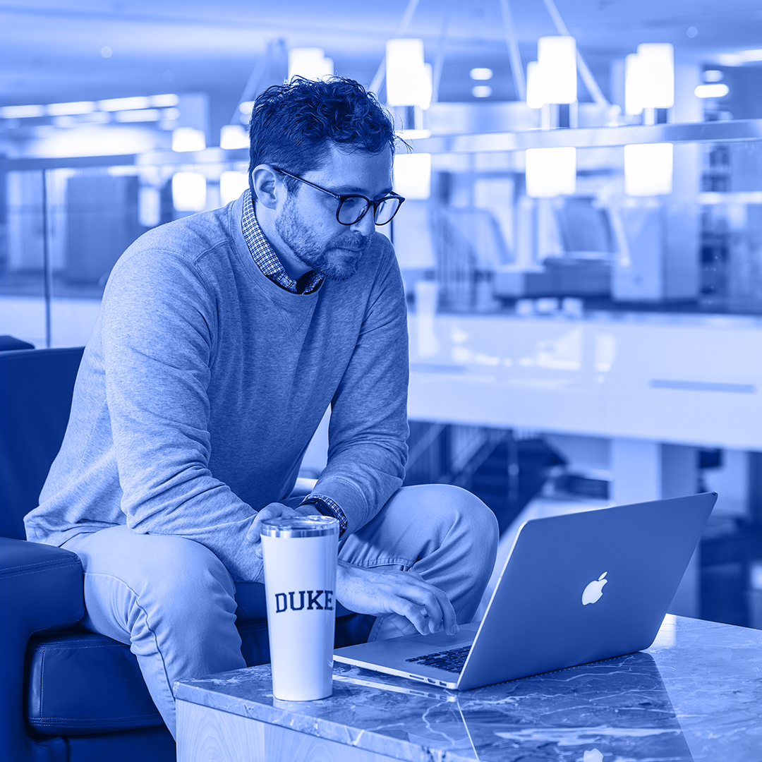a man sitting in front of a laptop in a library